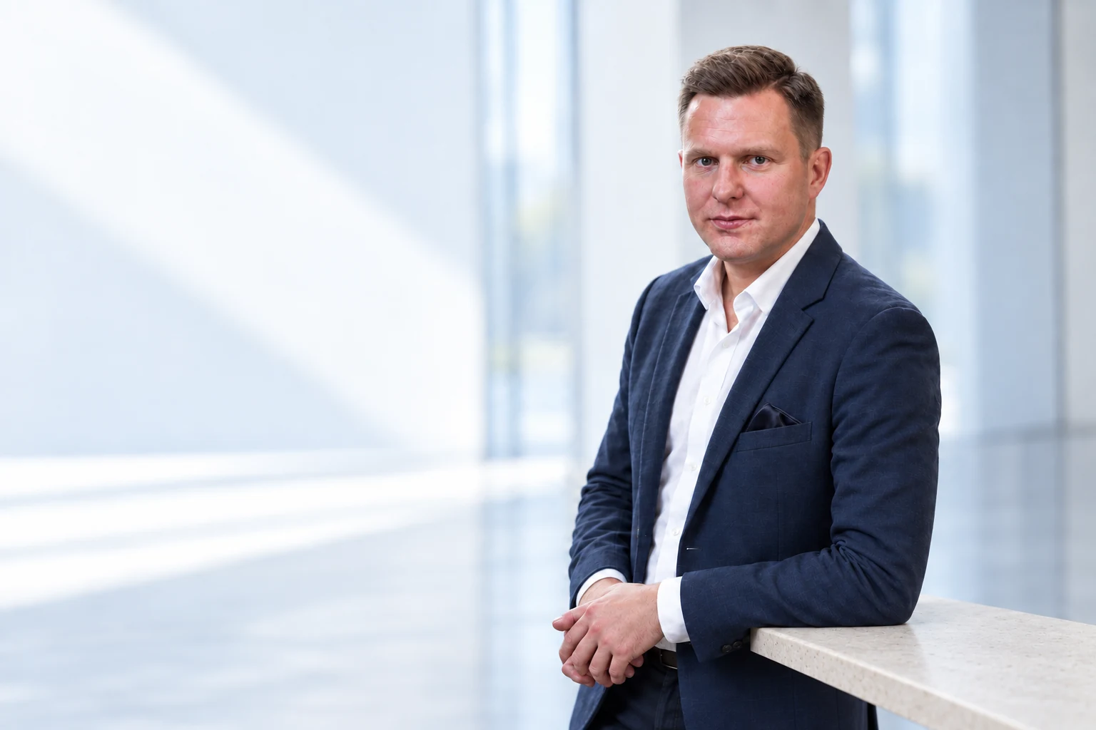 Grzegorz Kolasiński oparty o jasny kamienny blat